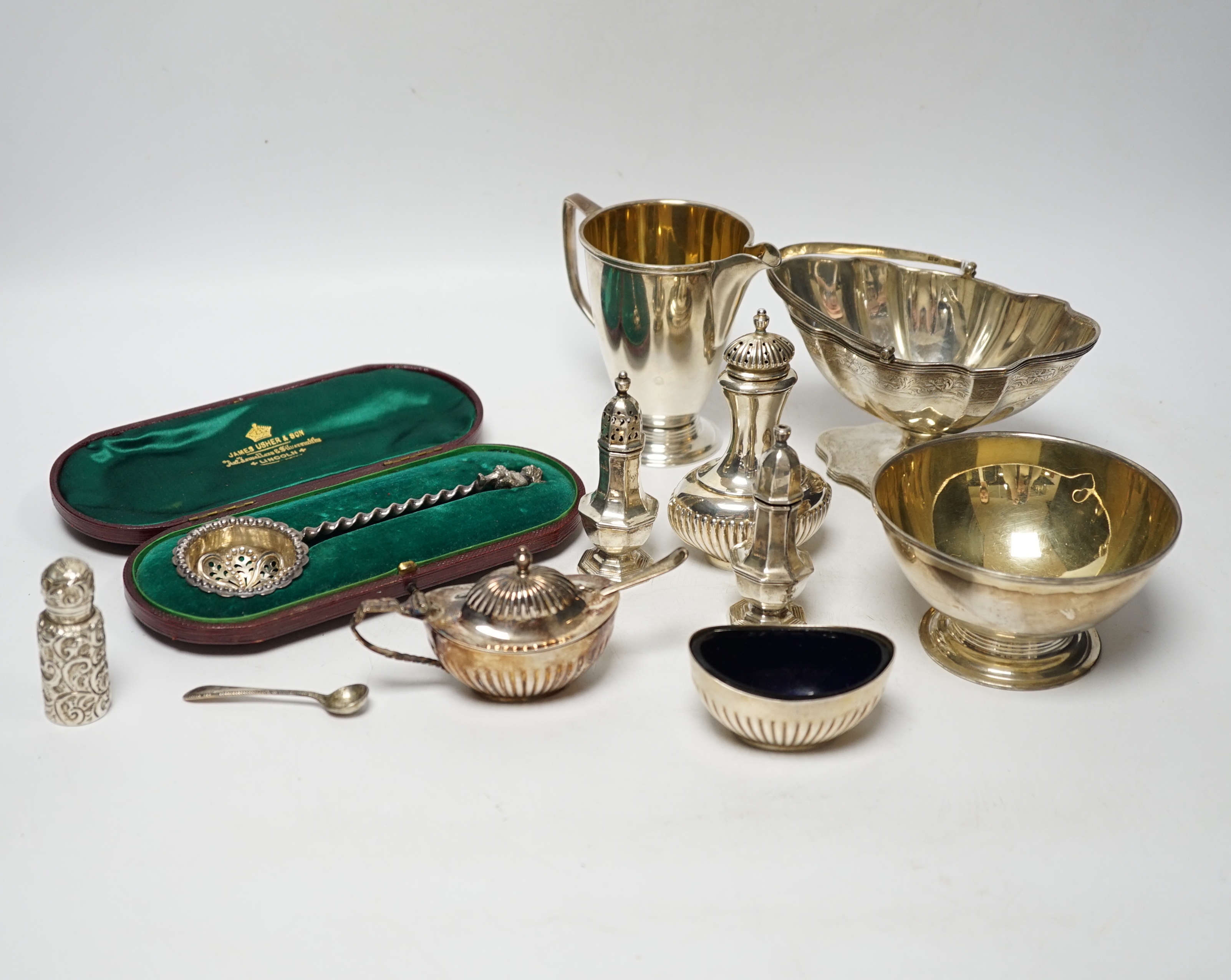 A group of small silver including Edwardian silver oval sugar basket, a modern silver cream jug and sugar bowl, five assorted condiments, a silver sifter spoon and a late Victorian scent bottle, 56mm.